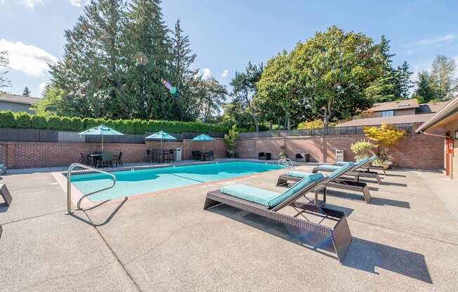 A pool with a diving board and sun loungers.