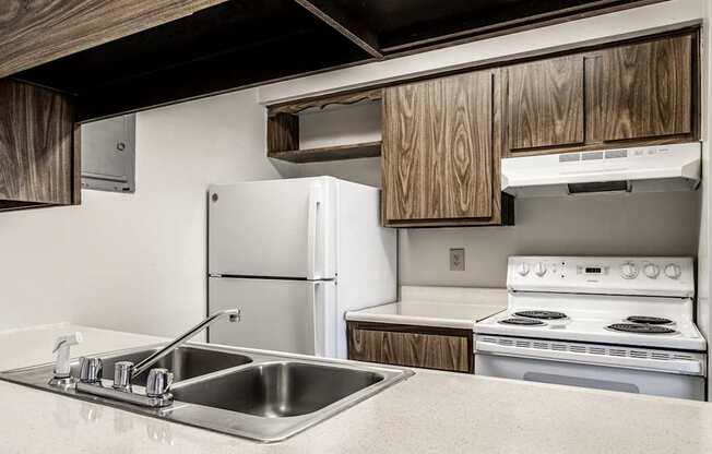 A kitchen with a stove, sink, and cabinets.