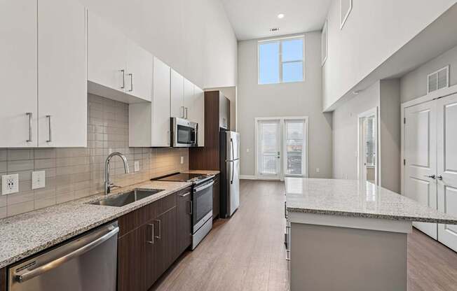 A modern kitchen with a large island and stainless steel appliances. A large bedroom with a ceiling fan and a window s. a large, high ceiling, apartment that has two floors, is a modern loft, and in atlanta