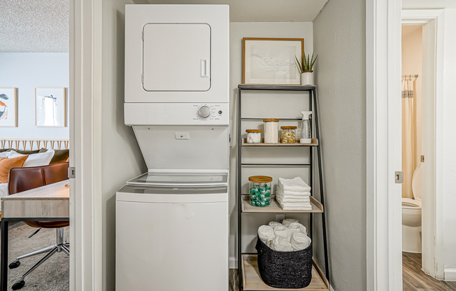 In-unit stacked washer and dryer next to shelves in Treehouse in Albuquerque, New Mexico