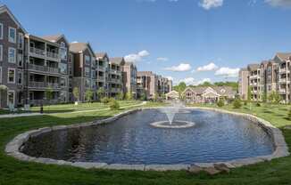 a large pond with a fountain in front of an apartment building at The Clearing at ONE28, Olathe