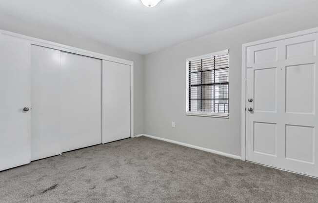 an empty bedroom with a closet and a door and a window