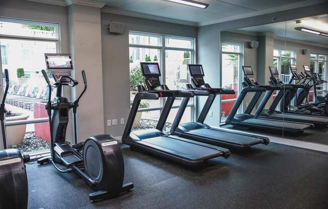 a row of treadmills and ellipticals in a gym