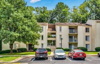 a parking lot in front of an apartment building with cars parked in front