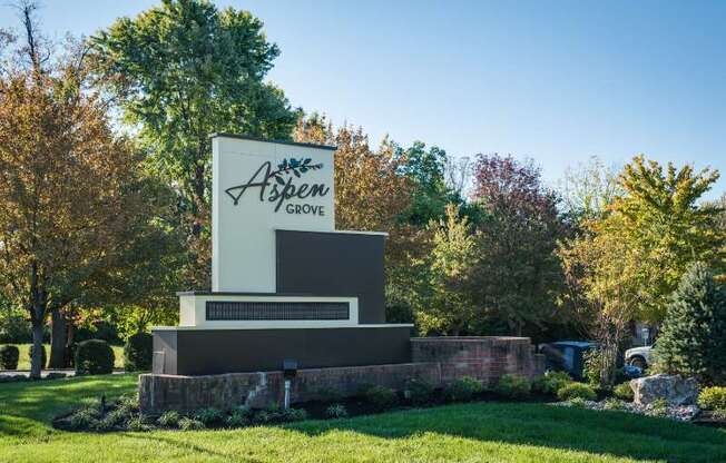 A sign that says Aspen Grove stands in a grassy field.