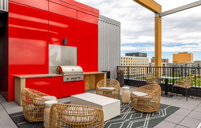 a rooftop patio with wicker chairs and a hot dog cart and a red wall