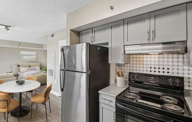 A modern kitchen with a refrigerator, stove, and dining table.
