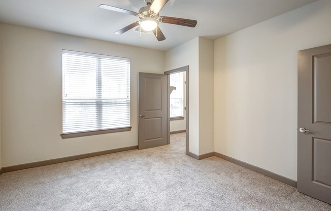 an empty living room with a ceiling fan and a window