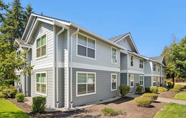 A grey two-story house with a white roof and multiple windows.