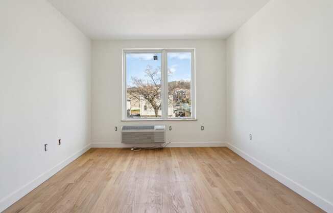 a living room with a large window and wooden floors