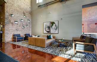 a living room with a couch and chairs and a brick wall