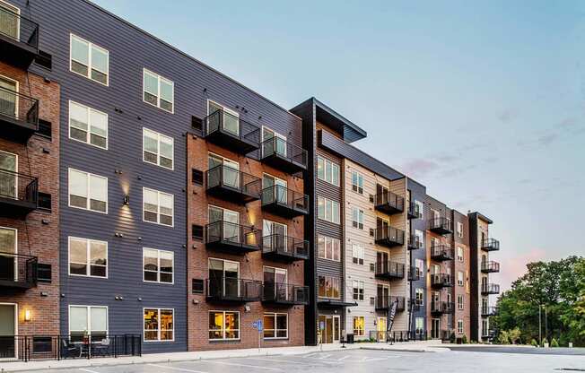 Exterior view of a modern six-story apartment complex featuring a harmonious blend of brick and metal siding. The architectural design showcases a contemporary aesthetic with clean lines and a mix of materials.
