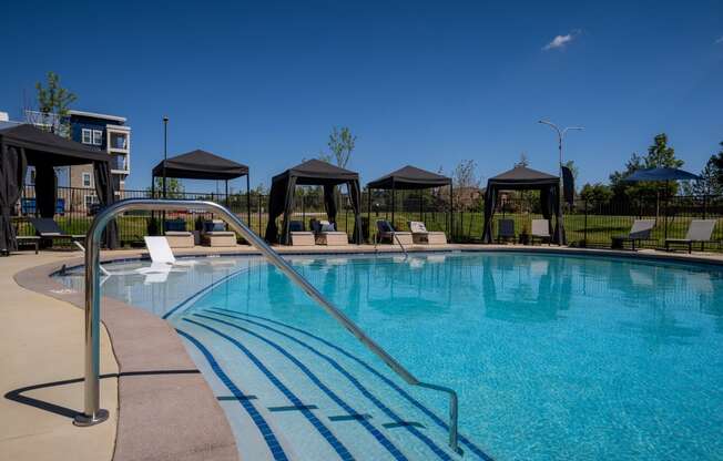 a swimming pool with chairs and gazebos and a blue sky above it