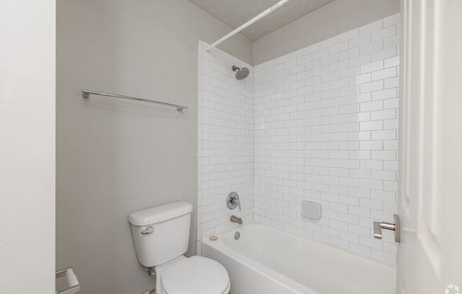 A white toilet sits next to a white bathtub in a bathroom.