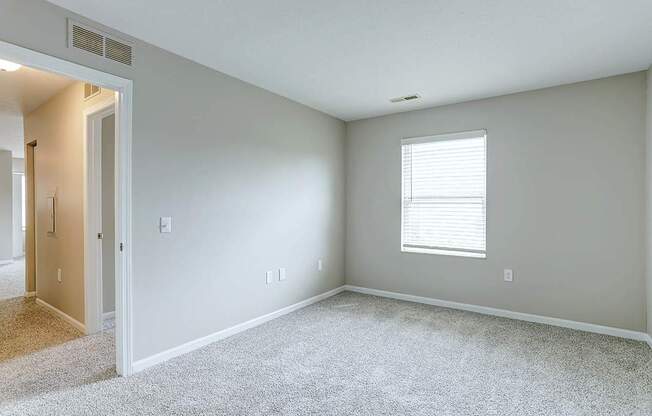 A room with a carpeted floor and a window with blinds.