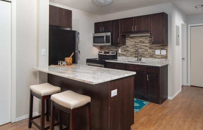 Stunning kitchen with breakfast bar, granite countertops and dark wood cabinets