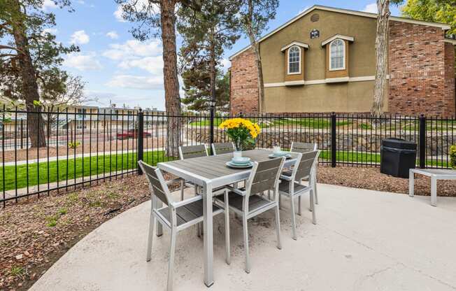 an outdoor patio with a table and chairs and a fence