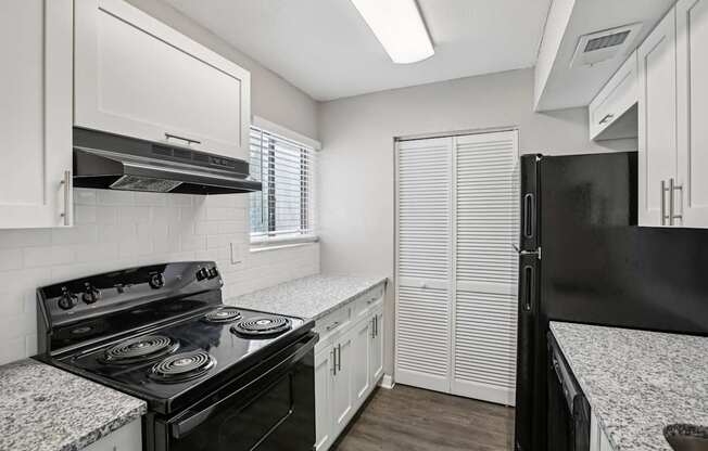 A black stove in a kitchen with white cabinets.