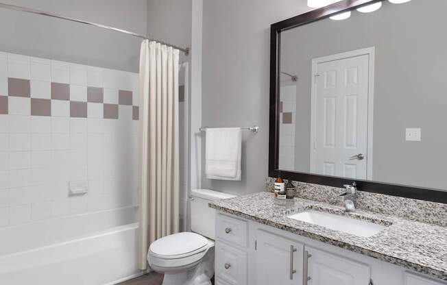 A bathroom with a toilet, sink, and mirror.