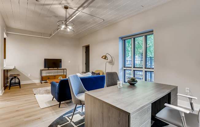 A room with a desk and chairs in front of a window.
