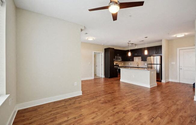 an empty living room and kitchen with a ceiling fan at Link Apartments® Brookstown, Winston Salem, NC