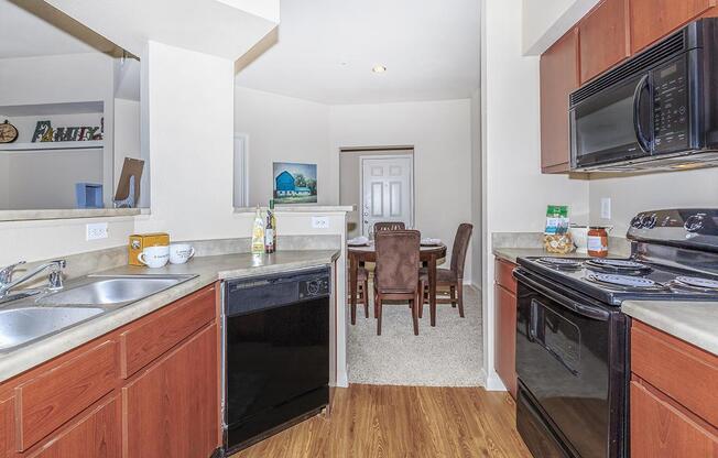 Kitchen with hardwood-style floors, black dishwasher and view of carpeted dining area