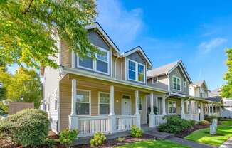 the front of a yellow house with trees and grass