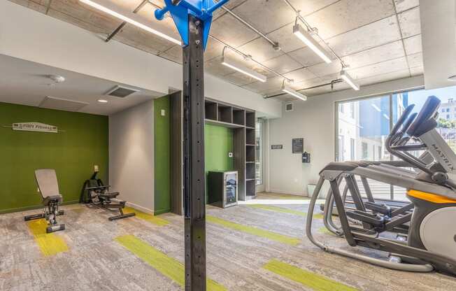 a gym with cardio equipment and green walls and a large window