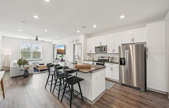 an open kitchen and living room with a stainless steel refrigerator at The Quarry Luxury Apartment Homes, Fort Collins, CO