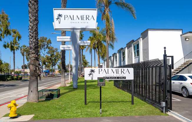 A sign for Palmera Chula Vista stands in front of a black fence.