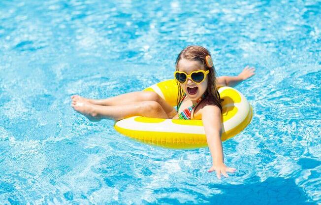 a girl in a swimming pool with a yellow float