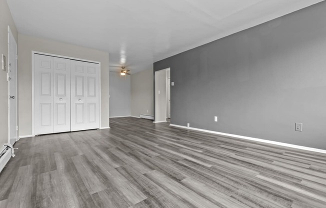 the living room and dining room of a new home with grey walls and wood floors