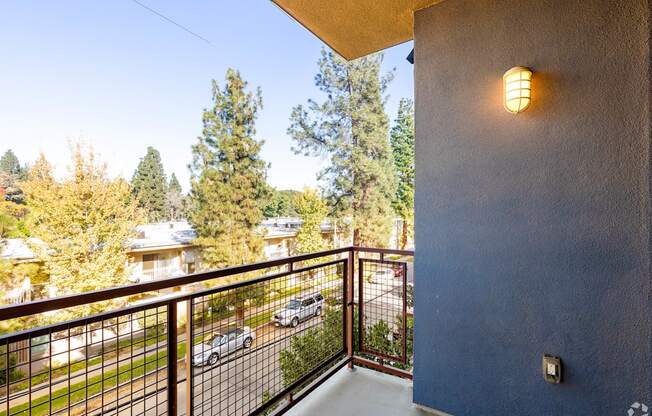 A balcony with a metal railing and a light on the wall.