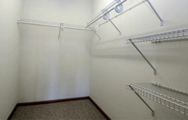 a walk in closet with white walls and two shelves on the wall