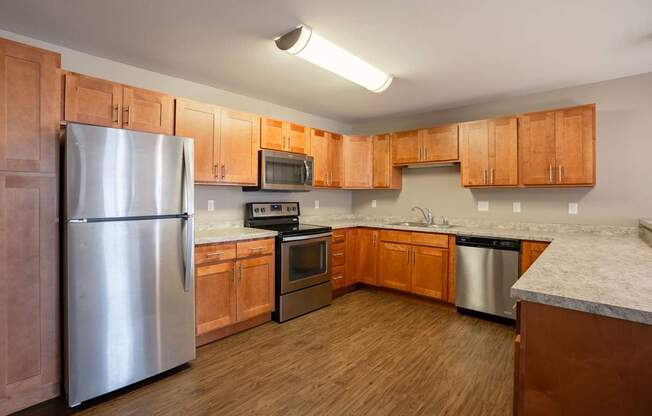 A kitchen with wooden cabinets and a stainless steel refrigerator. Fargo, ND Urban Plains Apartments