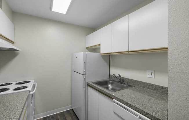 a kitchen with white cabinets and sink  at West Mall Place Apartment Homes, Everett