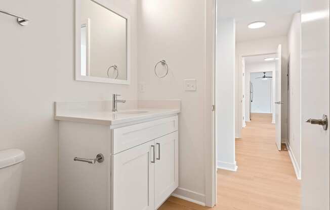 A white bathroom with a sink, mirror, and toilet.