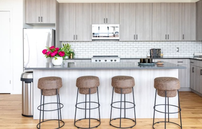 a kitchen with white cabinets and a counter with three stools