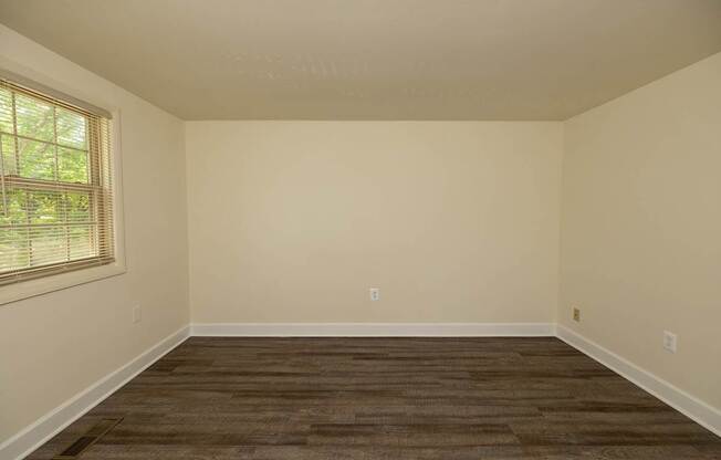 A room with a window and a brown floor.