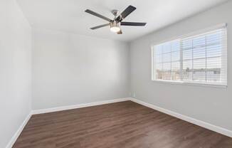 A room with a ceiling fan and a window with blinds.