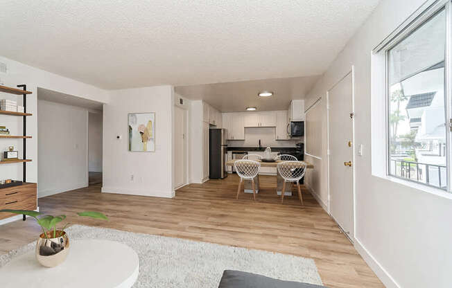 Model Living Room and Kitchen with Wood-Style Flooring at Palmilla Apartments located in San Diego, CA.