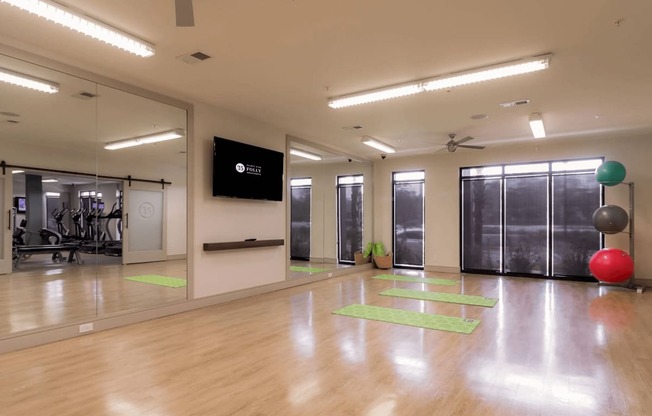 A gym with a mirror, exercise balls, and yoga mats.