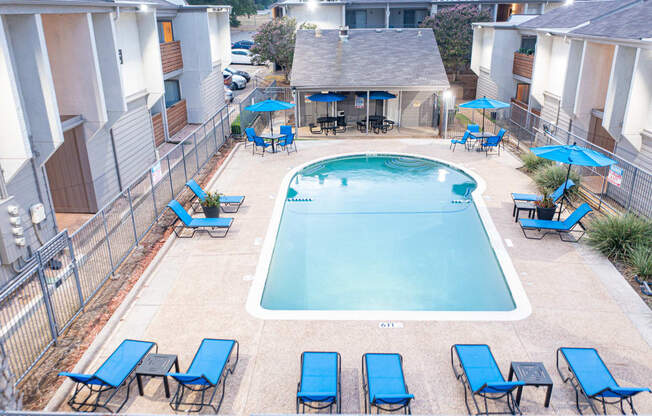 a swimming pool with blue chairs and umbrellas at the resort