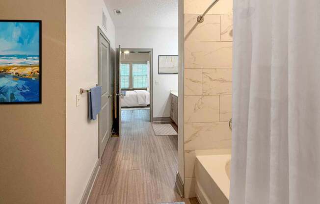 A bathroom with a white shower curtain and a wooden floor.