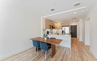 a dining room with a wooden table and chairs in front of a kitchen
