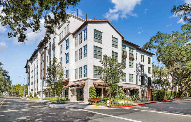 A large white building with a red awning sits on a street corner.