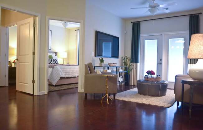 A bedroom with a bed, a couch, a chair, a table, and a ceiling fan.