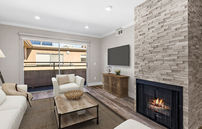 Living room with stone accented fireplace and balcony access.