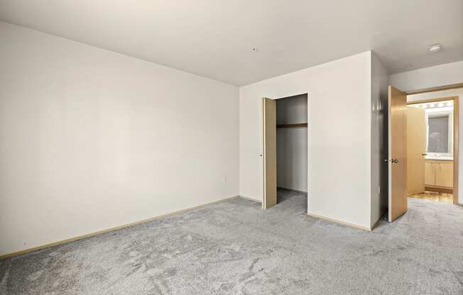 a bedroom with white walls and a carpeted floor at Mill Pond Apartments, Auburn