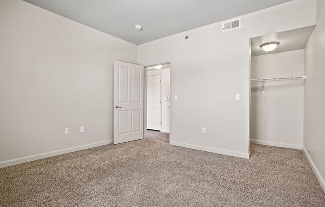 an empty living room with a closet and a door to a hallway